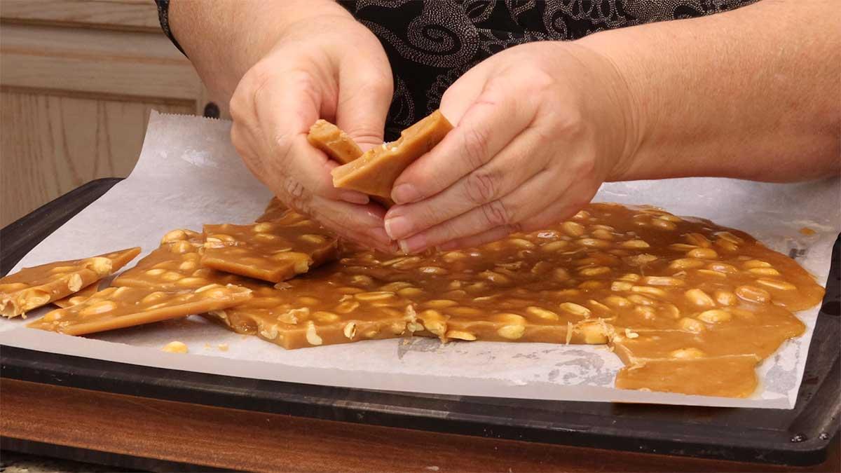 a person breaking peanut brittle into pieces