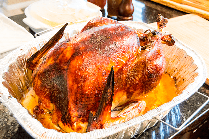 close-up shot of golden-brown crispy turkey skin with small pieces of sage leaves, glistening with melted butter, steam subtly rising