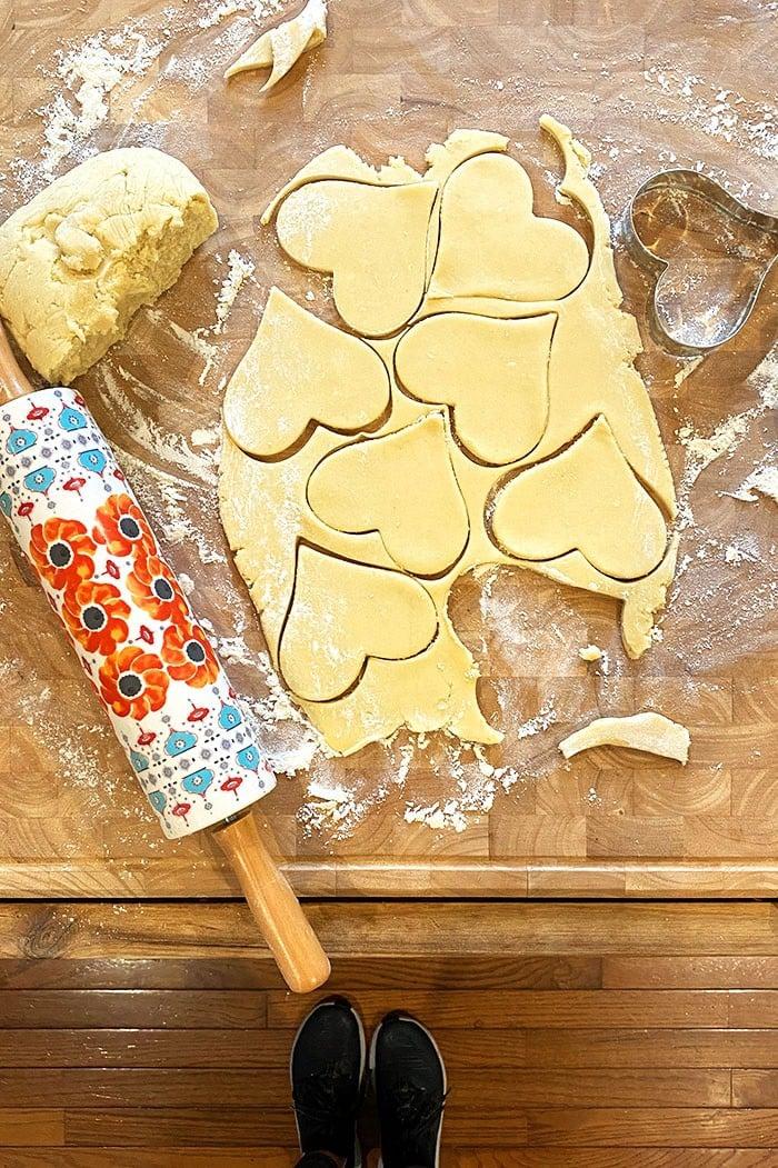 Overhead shot of various sugar cookie shapes being cut from rolled dough