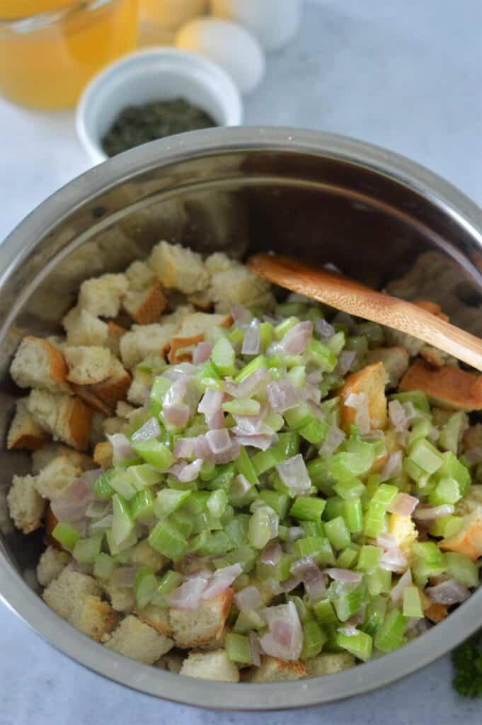 A close-up of a bowl filled with soft butter, finely chopped fresh sage, and minced garlic, ready to be mixed for the turkey rub.