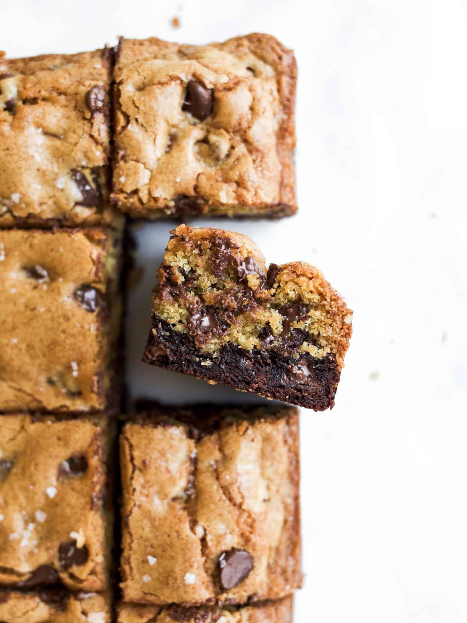 overhead shot of chocolate brownie cookie bars being sliced on a wooden board