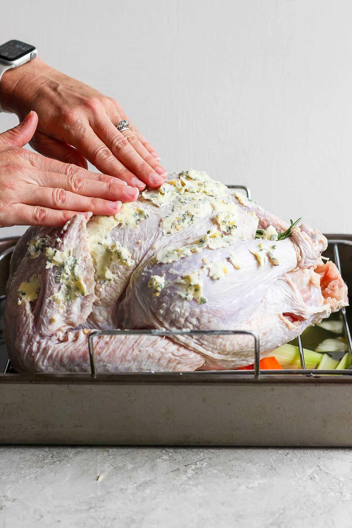 hands preparing herb butter to spread on a turkey