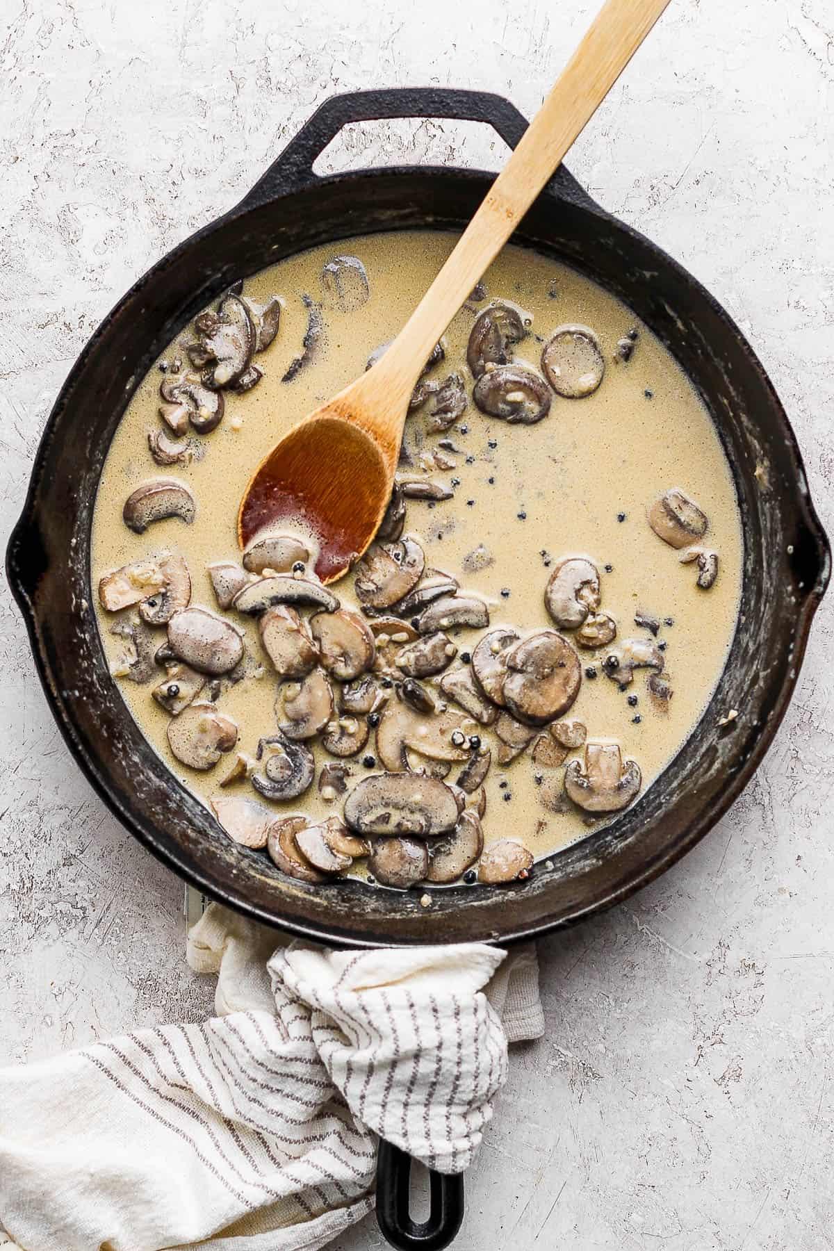 creamy mushroom sauce simmering in a skillet with fresh herbs