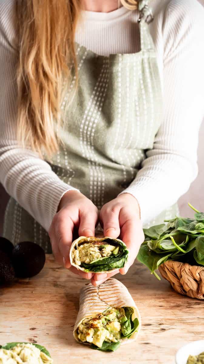 person assembling creamy chicken spinach wraps in a kitchen