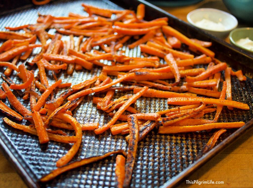 a tray of roasted carrot fries being served at an outdoor barbecue