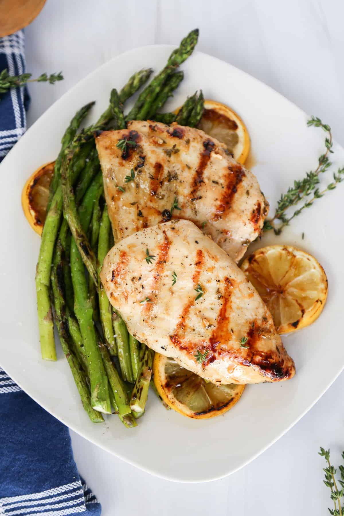 Cooked citrus garlic chicken breast sliced, served with roasted asparagus and lemon wedges