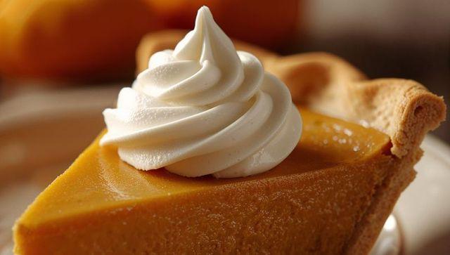 Warm slice of pumpkin pie with whipped cream swirl on a rustic table