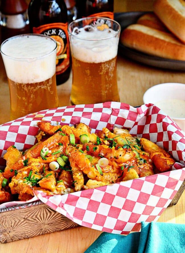 a plate of buffalo style carrot fries with blue cheese dressing alongside a glass of beer