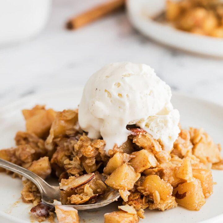 Slices of oatmeal apple crisp on plates, garnished with a scoop of vanilla ice cream and a sprinkle of cinnamon
