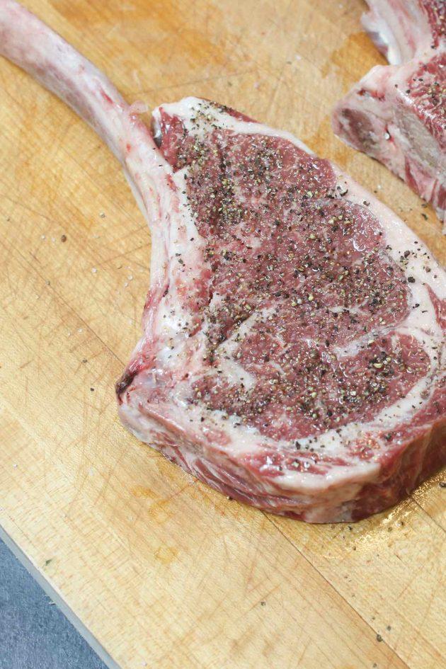 raw tomahawk steak seasoned with salt and pepper