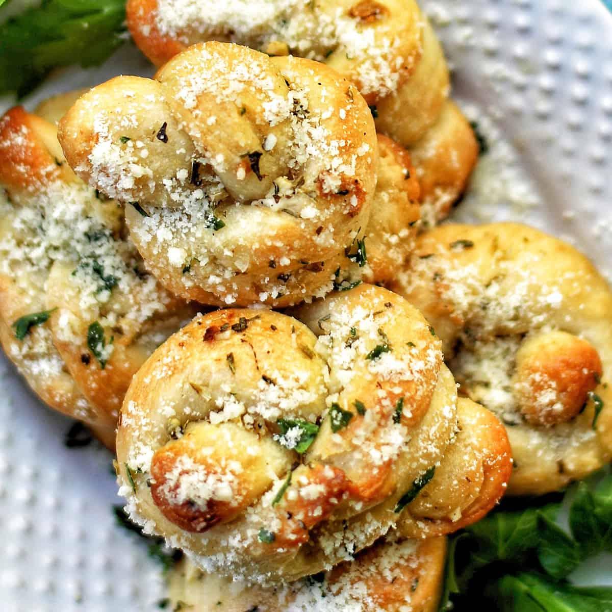 warm fluffy parmesan garlic knots with soft crumb, close-up, golden brown, melted cheese, fresh parsley, rustic wooden board, cinematic lighting