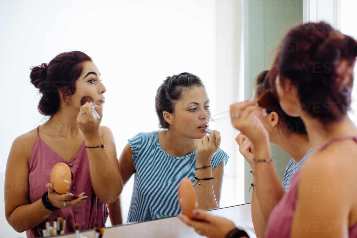 friends applying halloween makeup in a mirror
