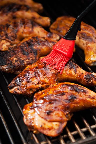XO sauce being brushed onto barbecue chicken on a grill