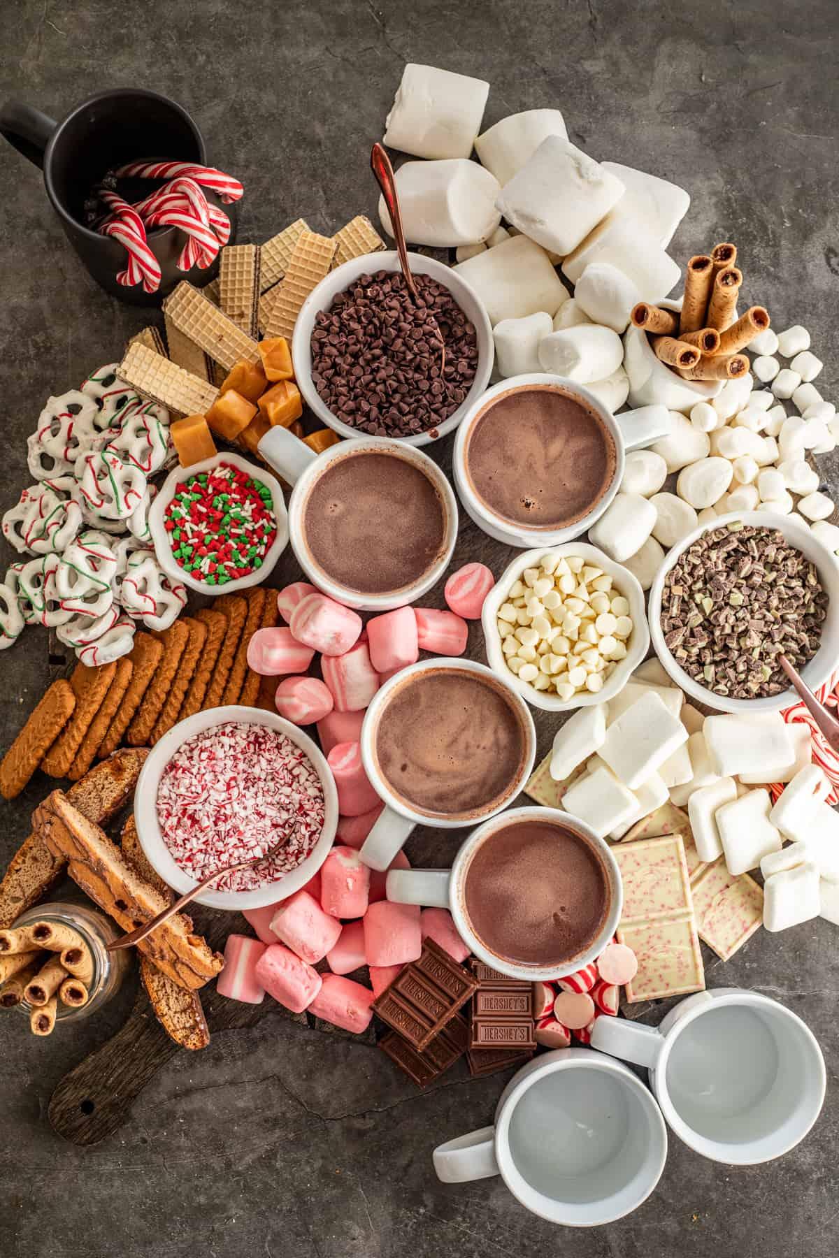 overhead shot of hot chocolate ingredients on a wooden board: chocolate bar, oranges, milk, spices