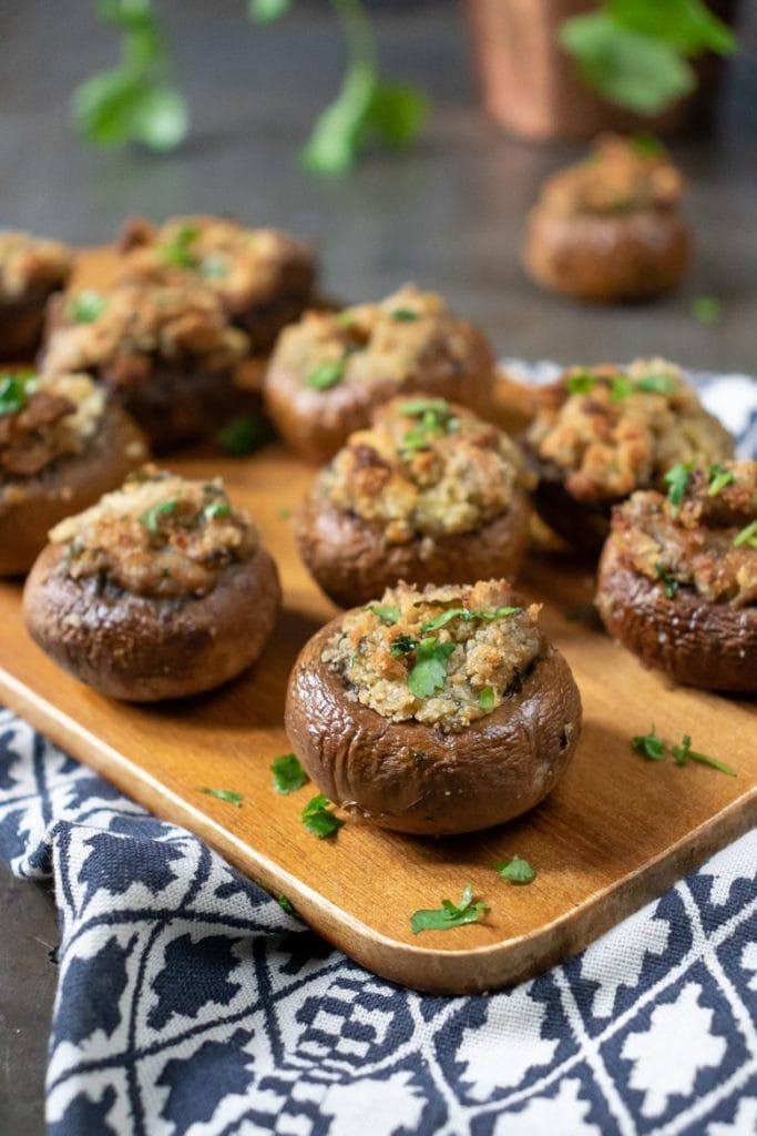Close-up of golden brown stuffed mushrooms with fresh herbs, rustic wooden board, natural light
