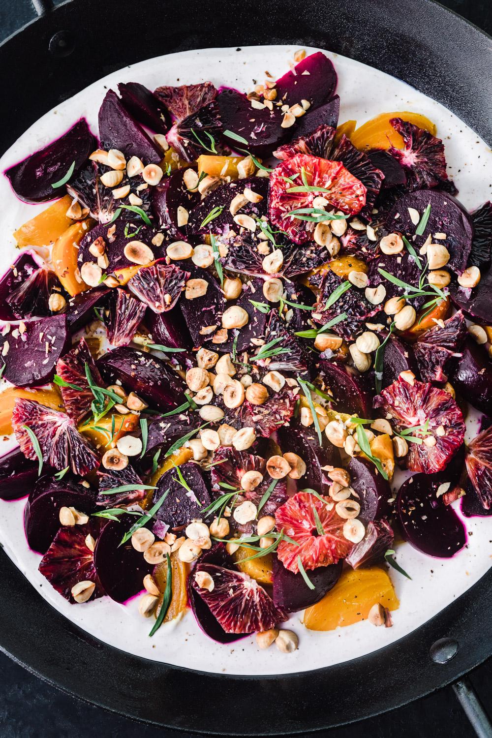 overhead shot of a colorful roasted beet salad with fresh herbs and a drizzle of dressing