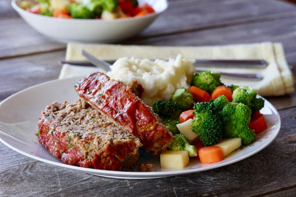 Meatloaf dish with green vegetables around it