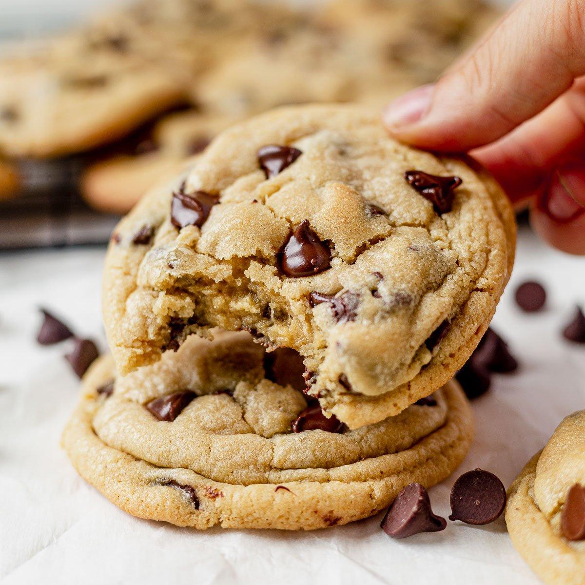 A smiling person taking a bite of a chocolate chip cookie