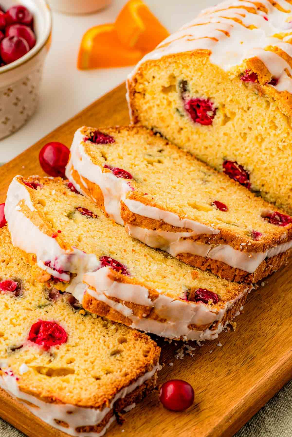 Warm cranberry orange loaf bread with vanilla icing drizzle on a cooling rack, cozy kitchen setting