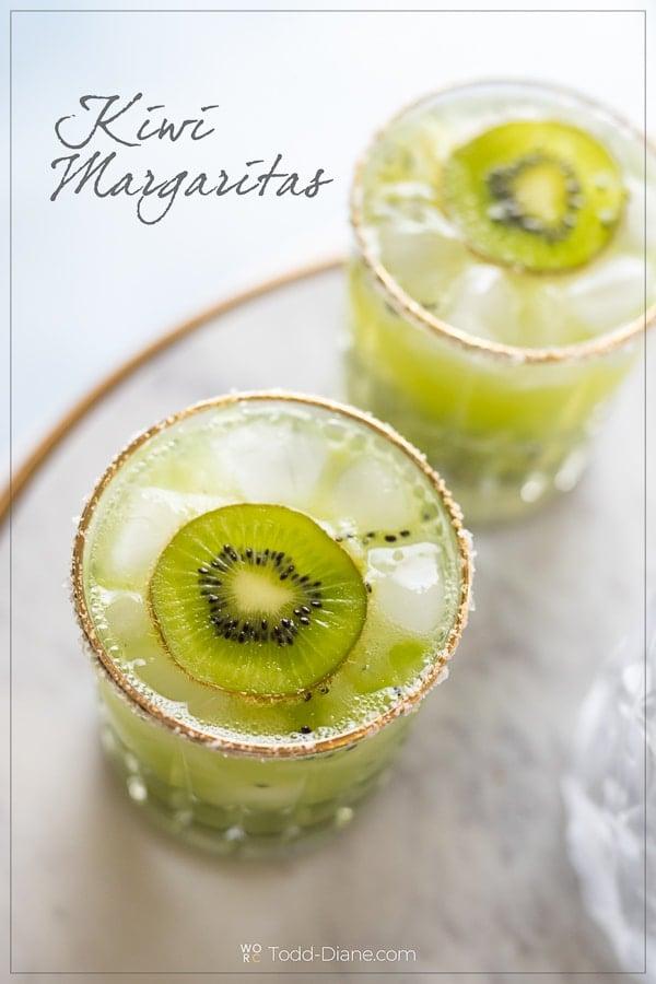 Kiwi margarita with lime wedge and salt rim, garnished with edible flowers