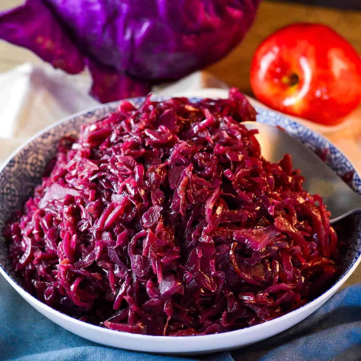 braised red cabbage cooking in a cast iron pot on a stove