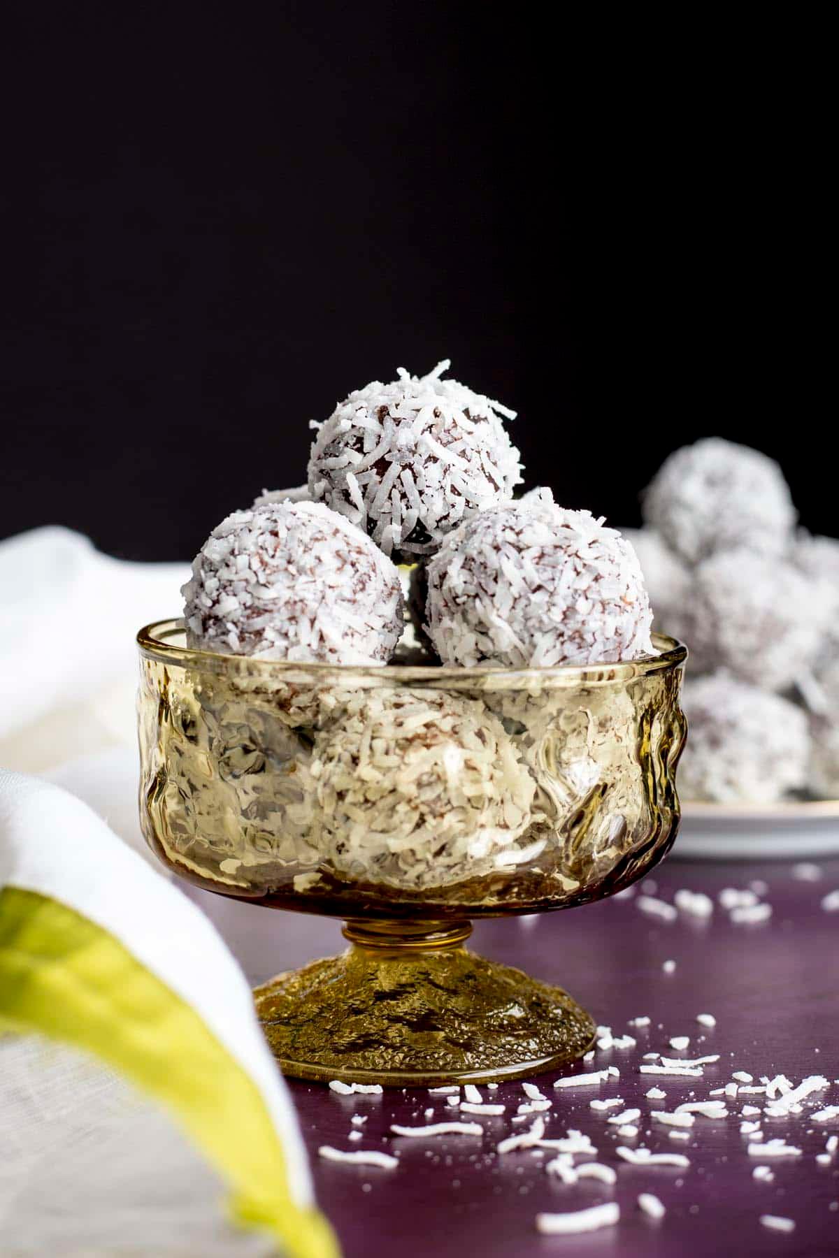 ingredients for coconut truffles, including shredded coconut, condensed milk, and butter, laid out on a rustic wooden table