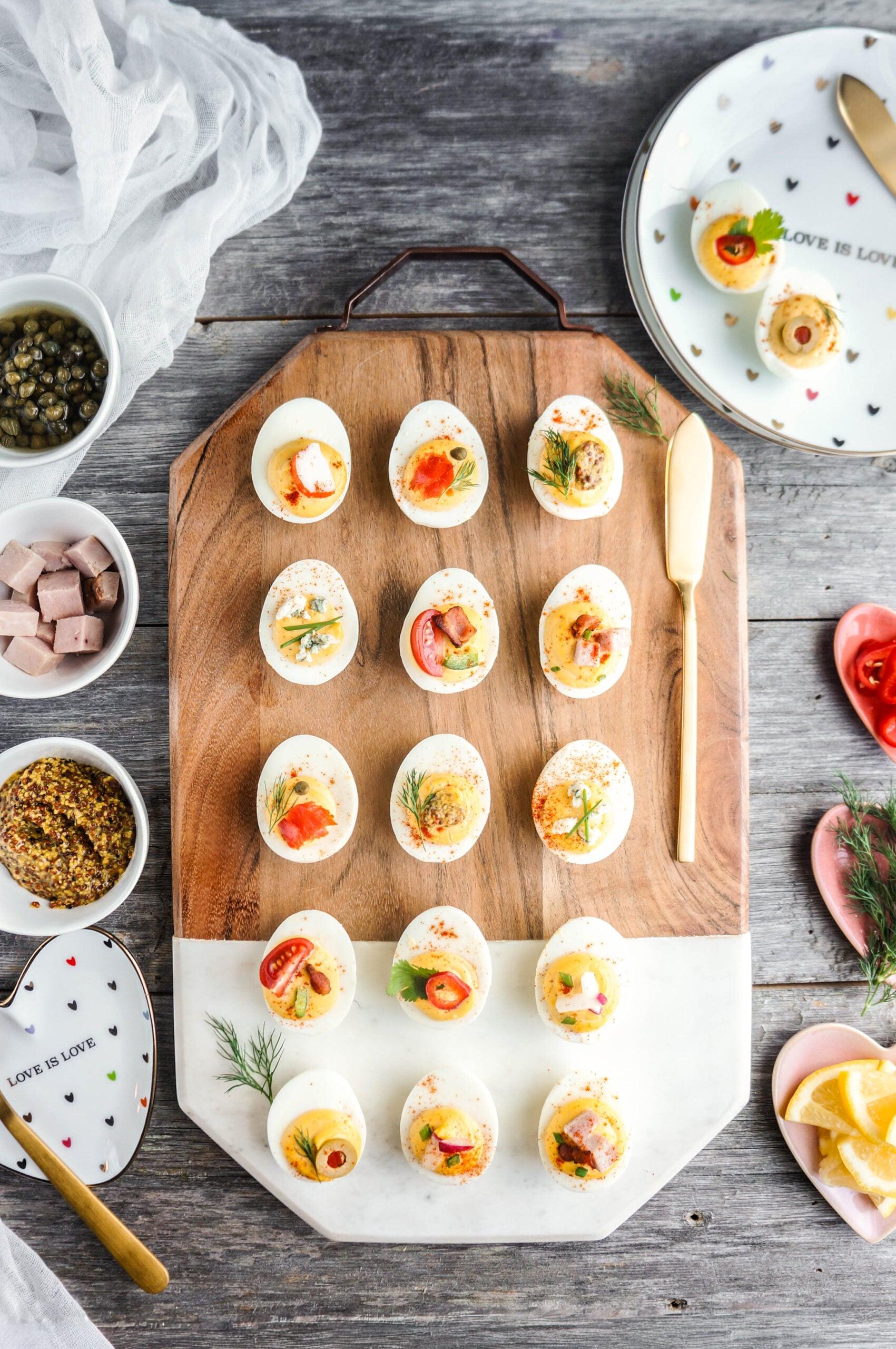 Overhead shot of all ingredients for deviled eggs laid out on a wooden cutting board