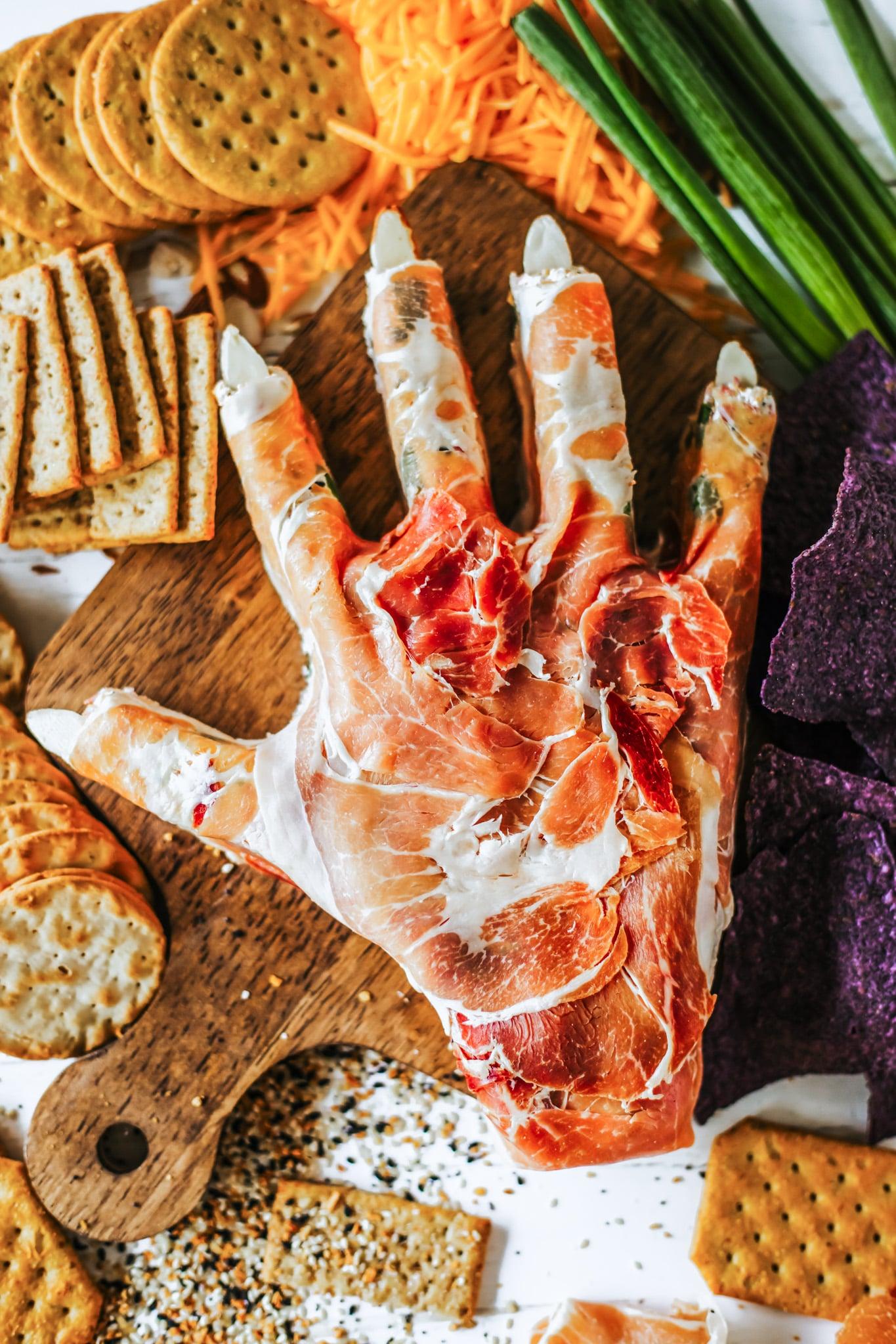 Pile of cheese pastry bites on a wooden board, with a hand reaching for one