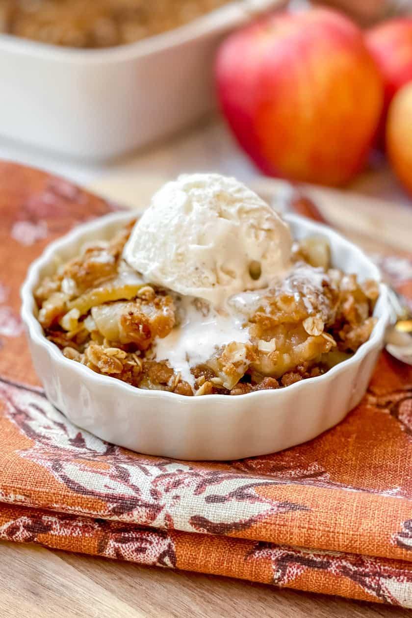 Warm apple crumble serving, topped with melting vanilla ice cream, close-up