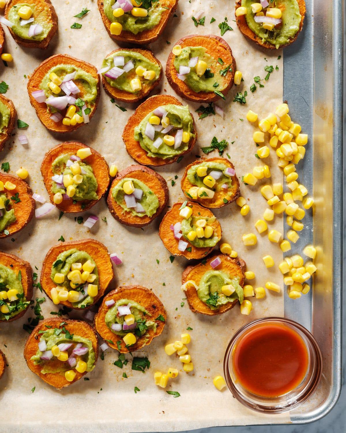 Hands reaching for a bowl of sweet potato bites at a rustic fall potluck.