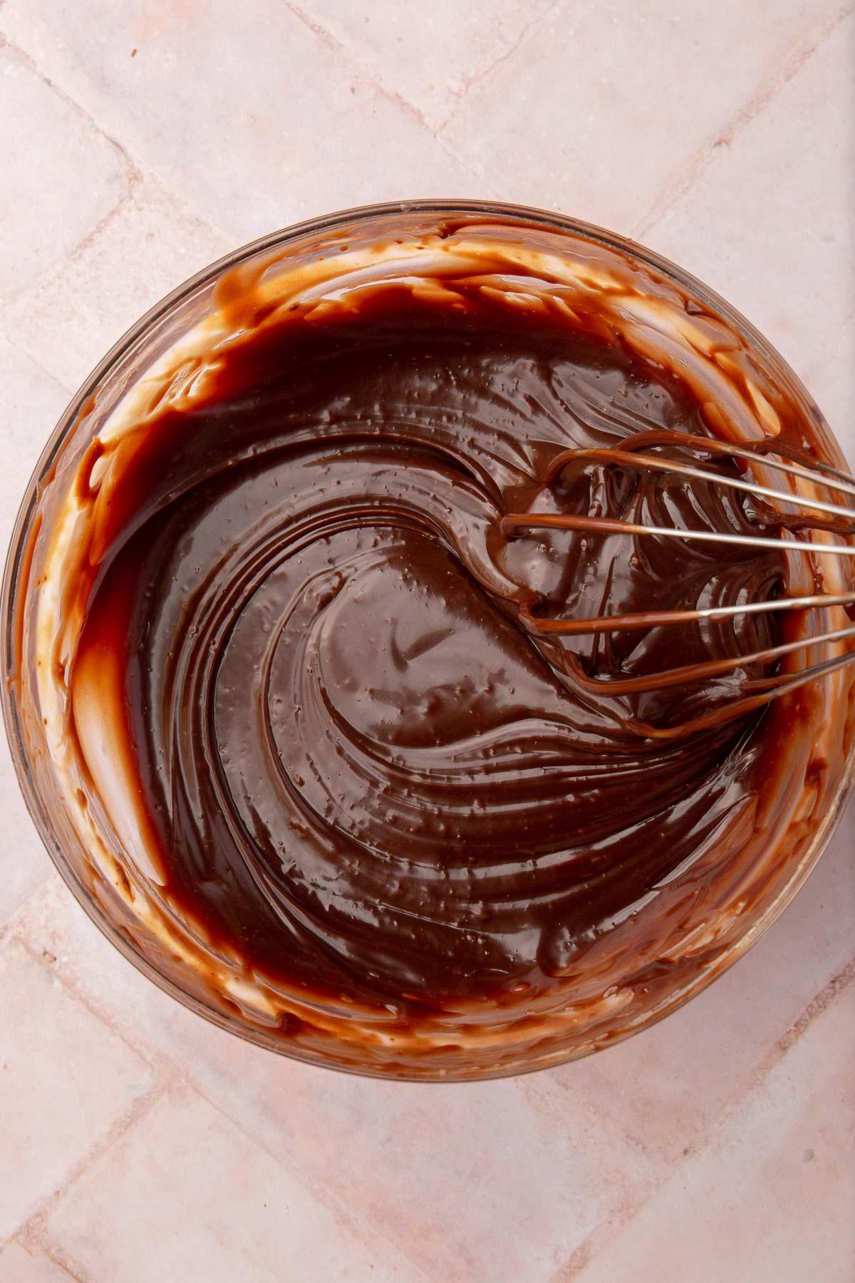 Close-up shot of rich ganache mixture being stirred in a bowl
