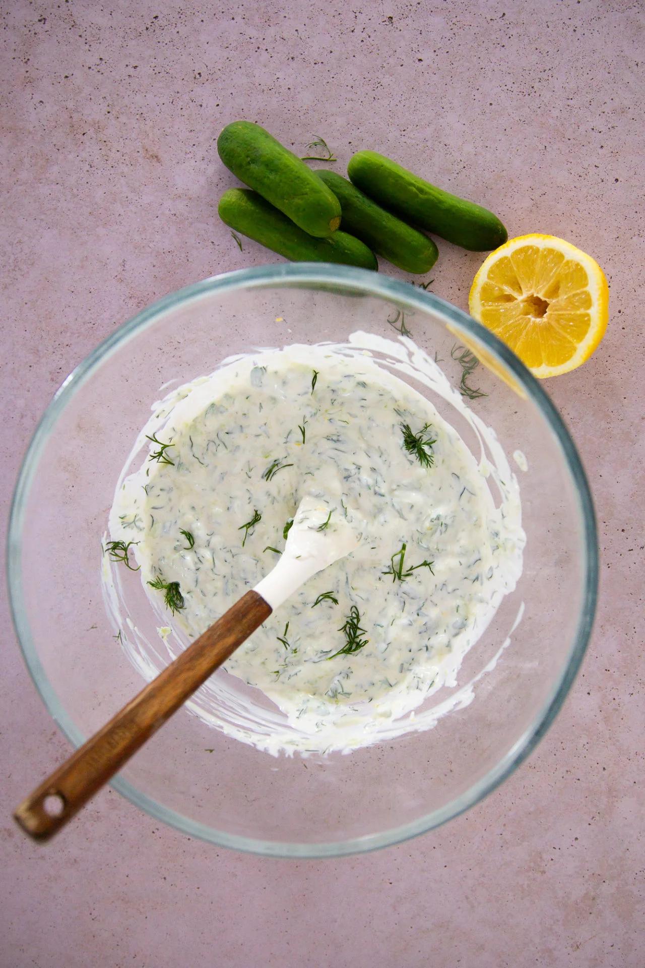 Close-up of freshly made tzatziki sauce in a white bowl with chopped cucumber and dill