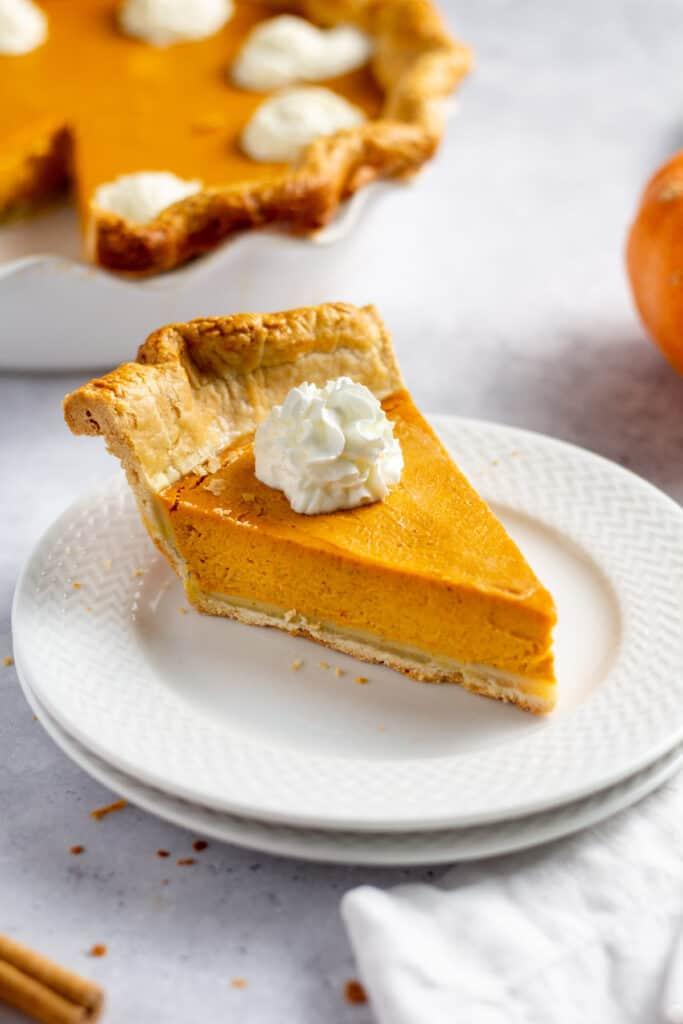 slice of soft vanilla pumpkin pie with whipped cream on a plate