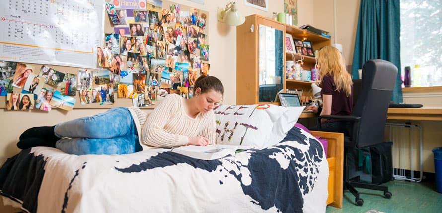 Student hunched over in a cramped dorm room studying