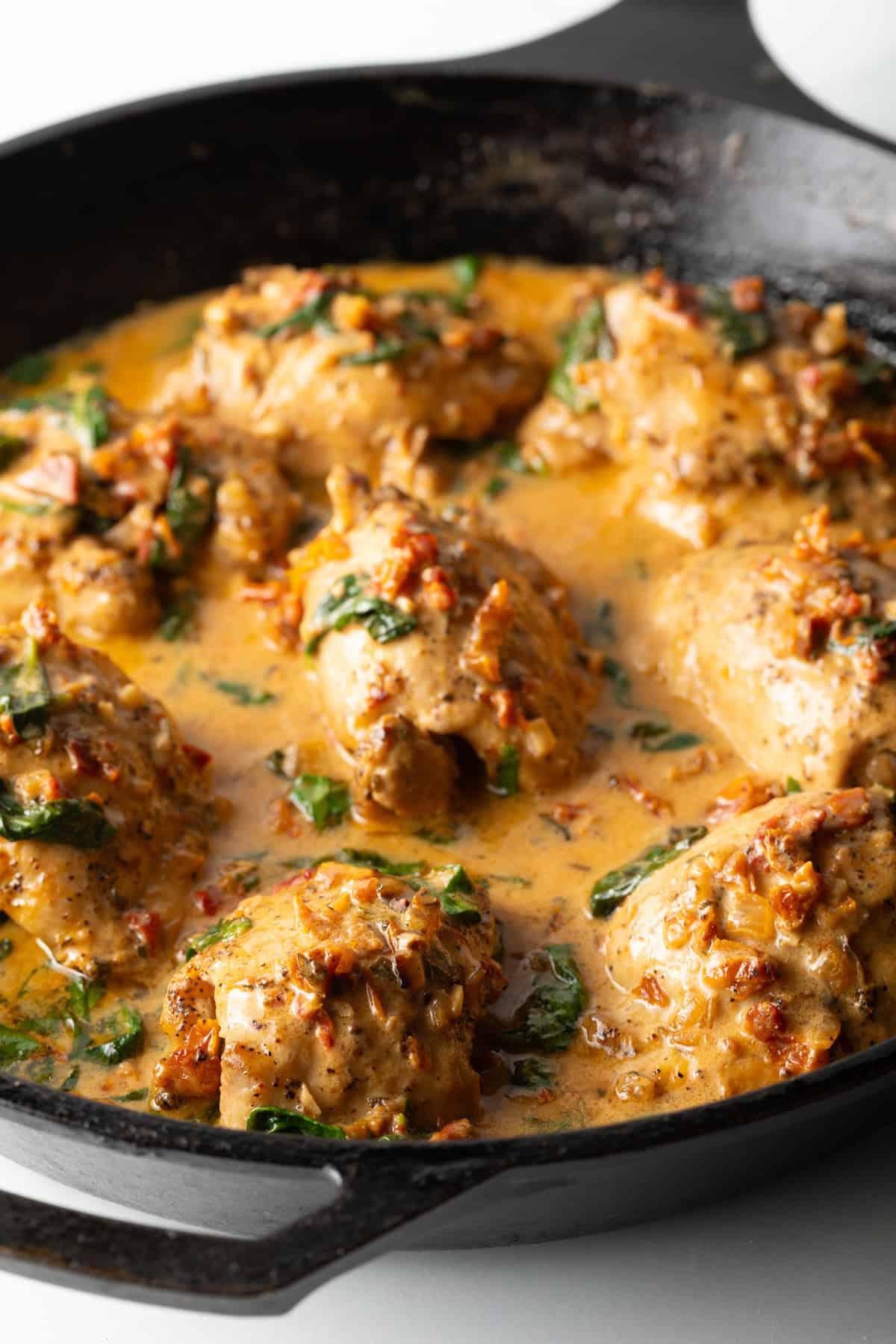 creamy tuscan chicken simmering in a cast iron skillet