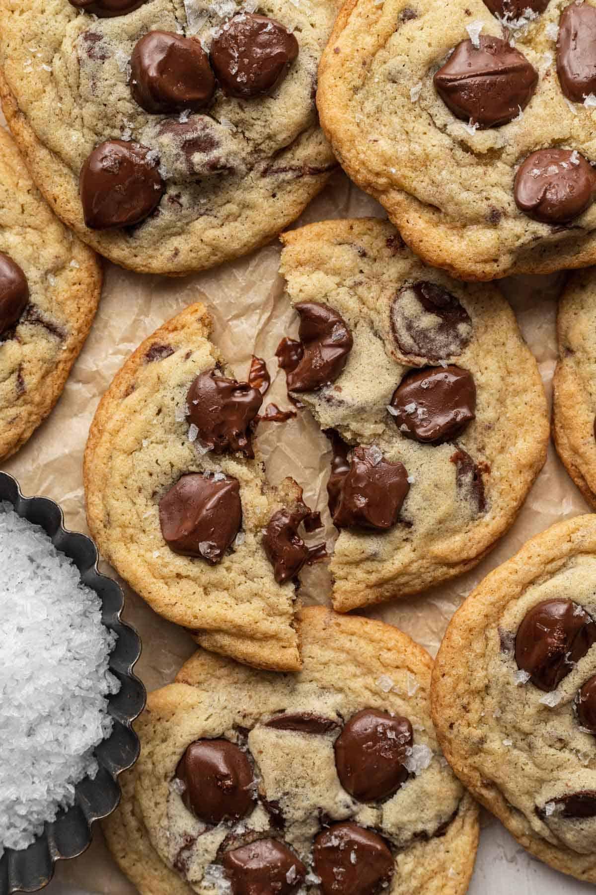 Close-up of baked chocolate chip cookies with visible flaky sea salt on top, steam gently rising