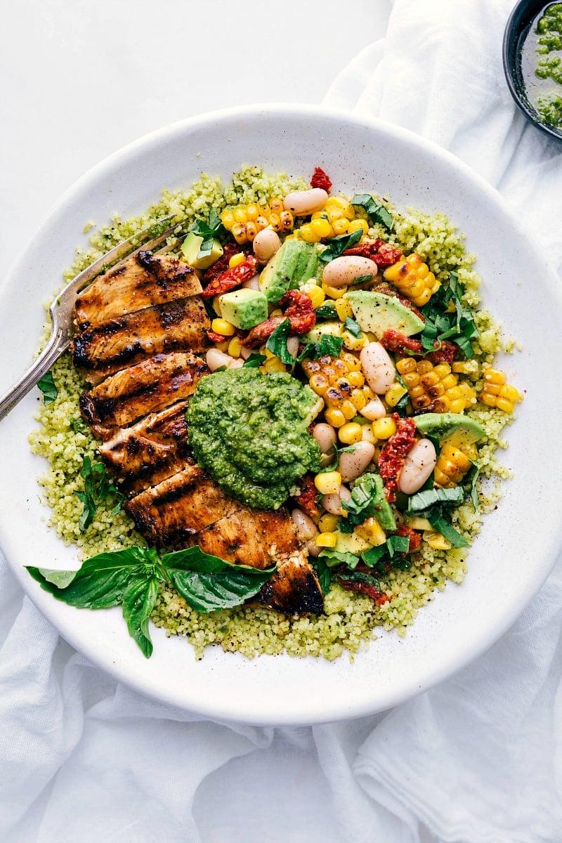 Close-up shot of the pesto-coated chicken in the bowl, highlighting the fresh basil and vibrant colors