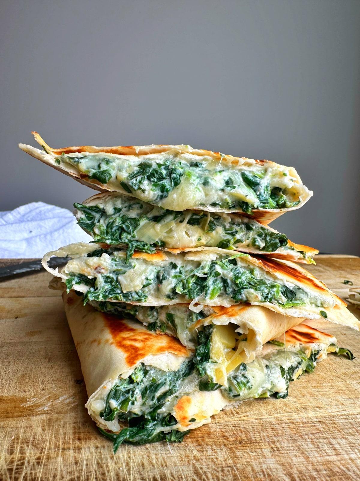 overhead shot of freshly made spinach and ricotta quesadillas on a wooden cutting board