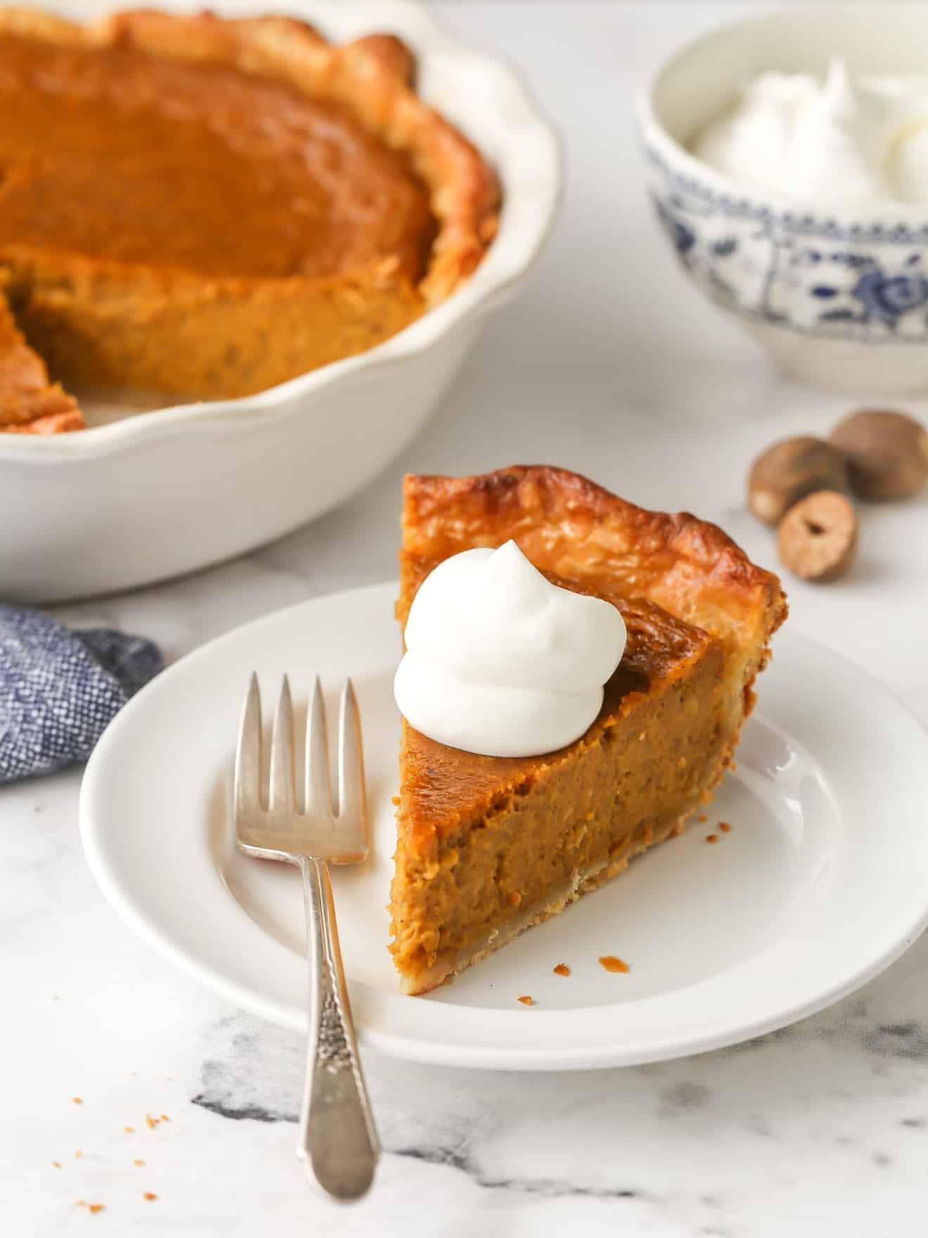 beautifully baked classic pumpkin pie, golden brown crust, smooth orange custard, autumn leaves background, rustic kitchen setting