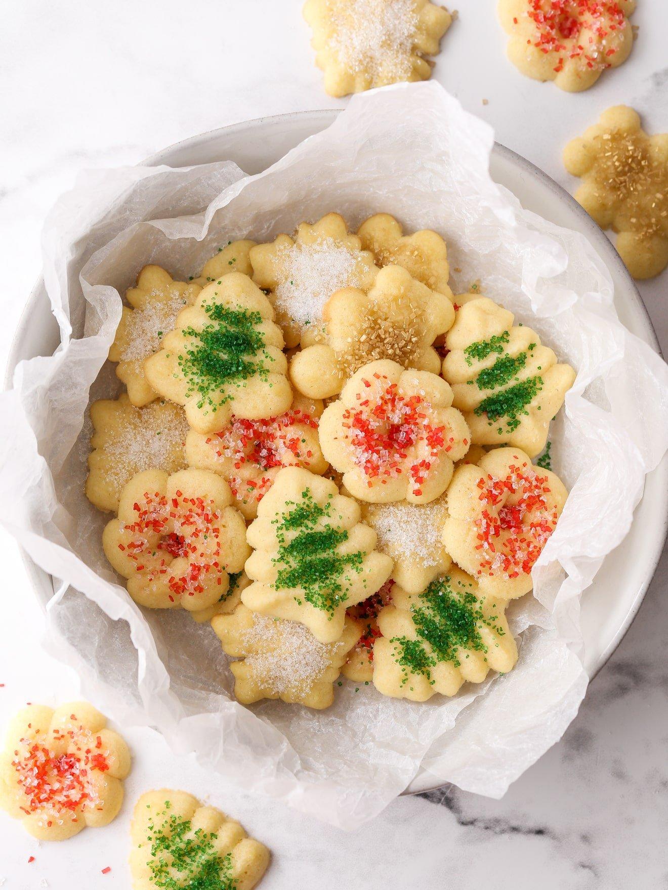 Beautifully arranged plate of golden butter spritz cookies with a holiday background, focus on crisp texture