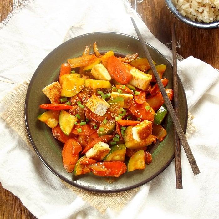 chef stir frying tofu and kimchi with vegetables