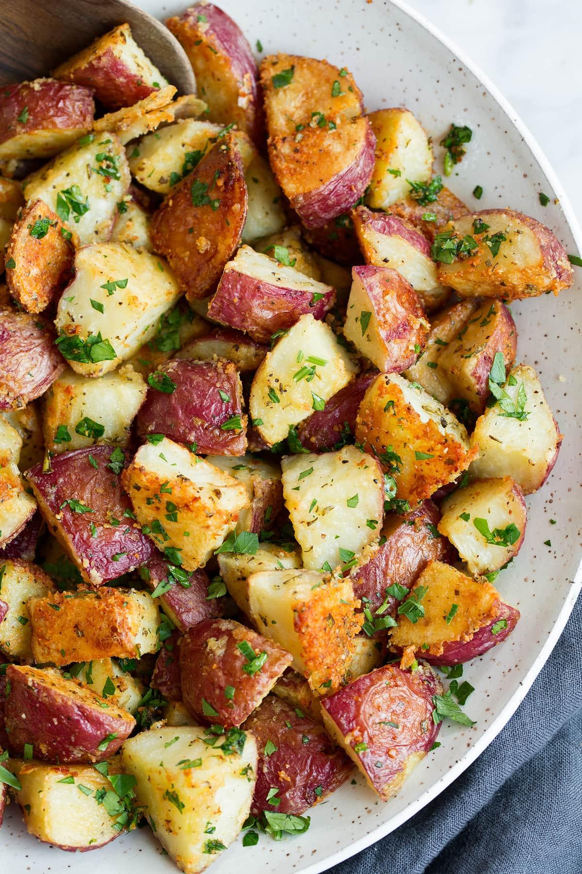 close-up of golden brown parmesan roasted potatoes with fresh herbs