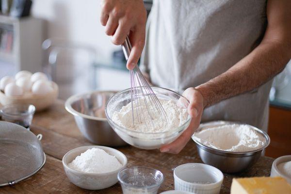Hands gently placing smooth white chocolate drops onto a cooling rack
