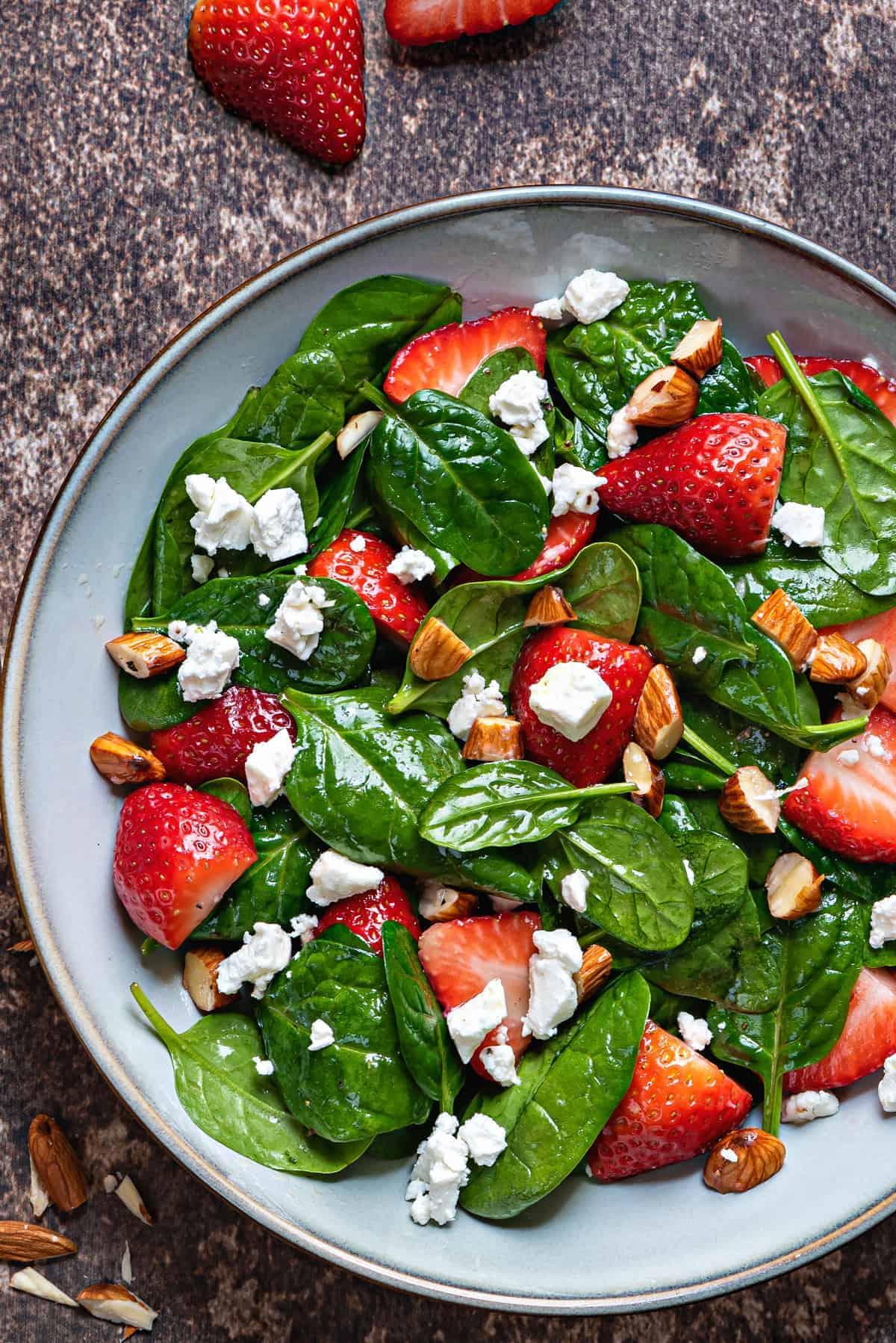 a close-up shot of a freshly tossed strawberry spinach salad