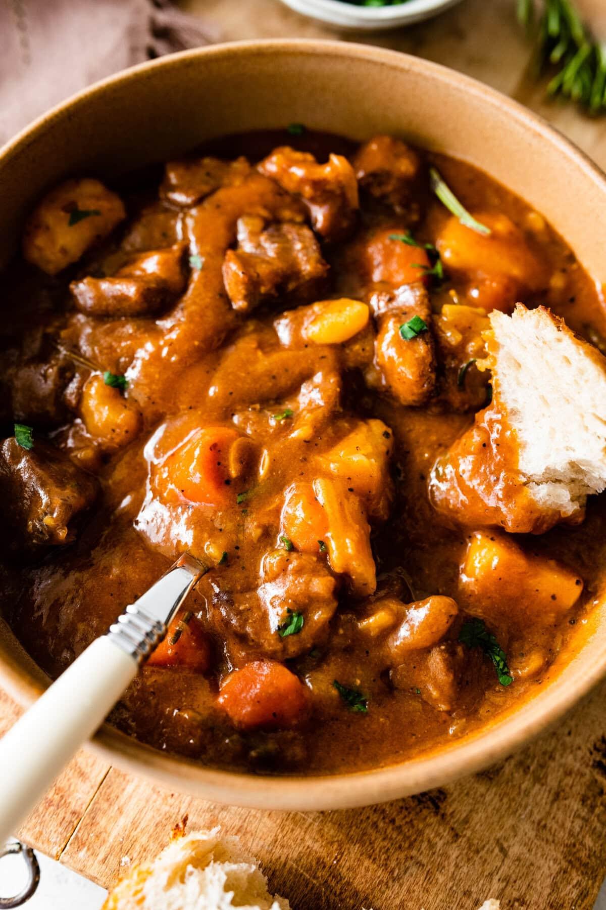 Bowl of beef stew garnished with fresh parsley, ready to eat
