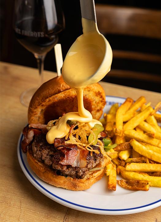 Gourmet smash burger with melted cheese and secret sauce dripping, served with crispy fries