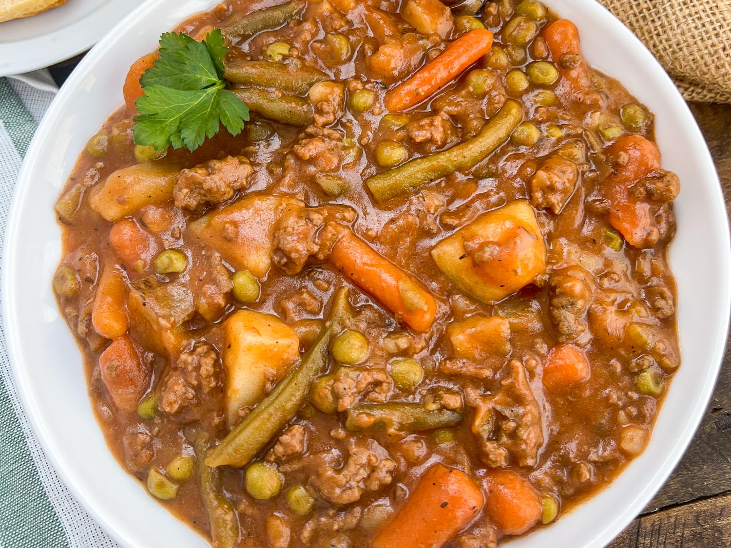 Close-up of rustic beef ground stew simmering in a cast iron pot, showing chunks of beef and vegetables