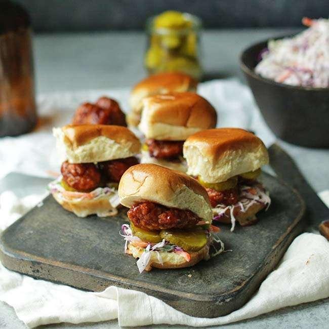 Overhead shot of blackberry bbq chicken sliders, served with coleslaw and pickles