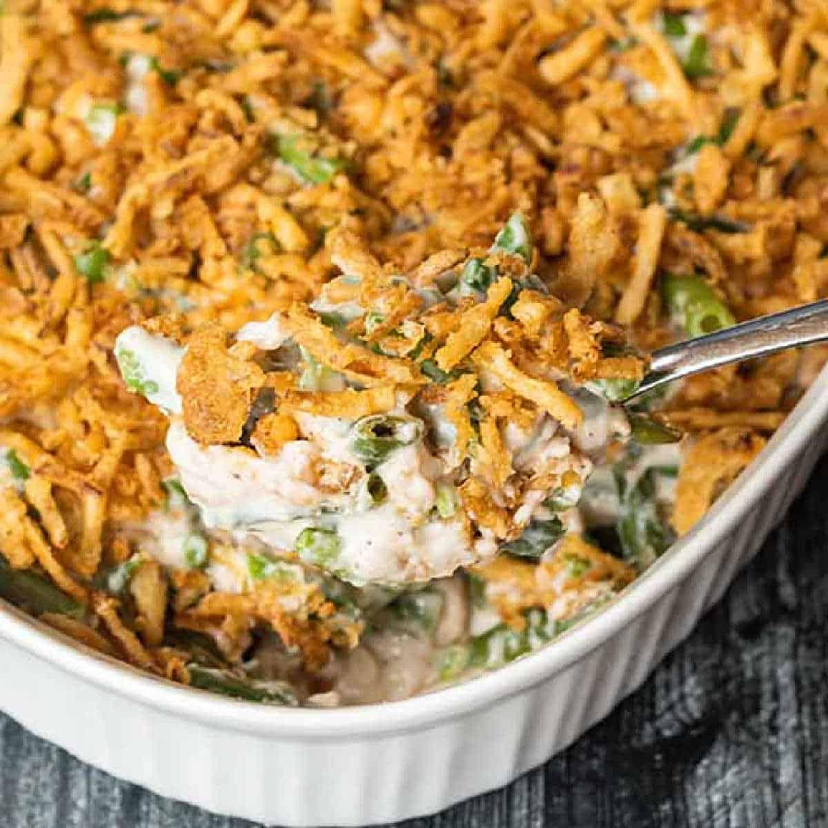 close up of creamy green bean casserole with crispy golden onions bubbling in a baking dish