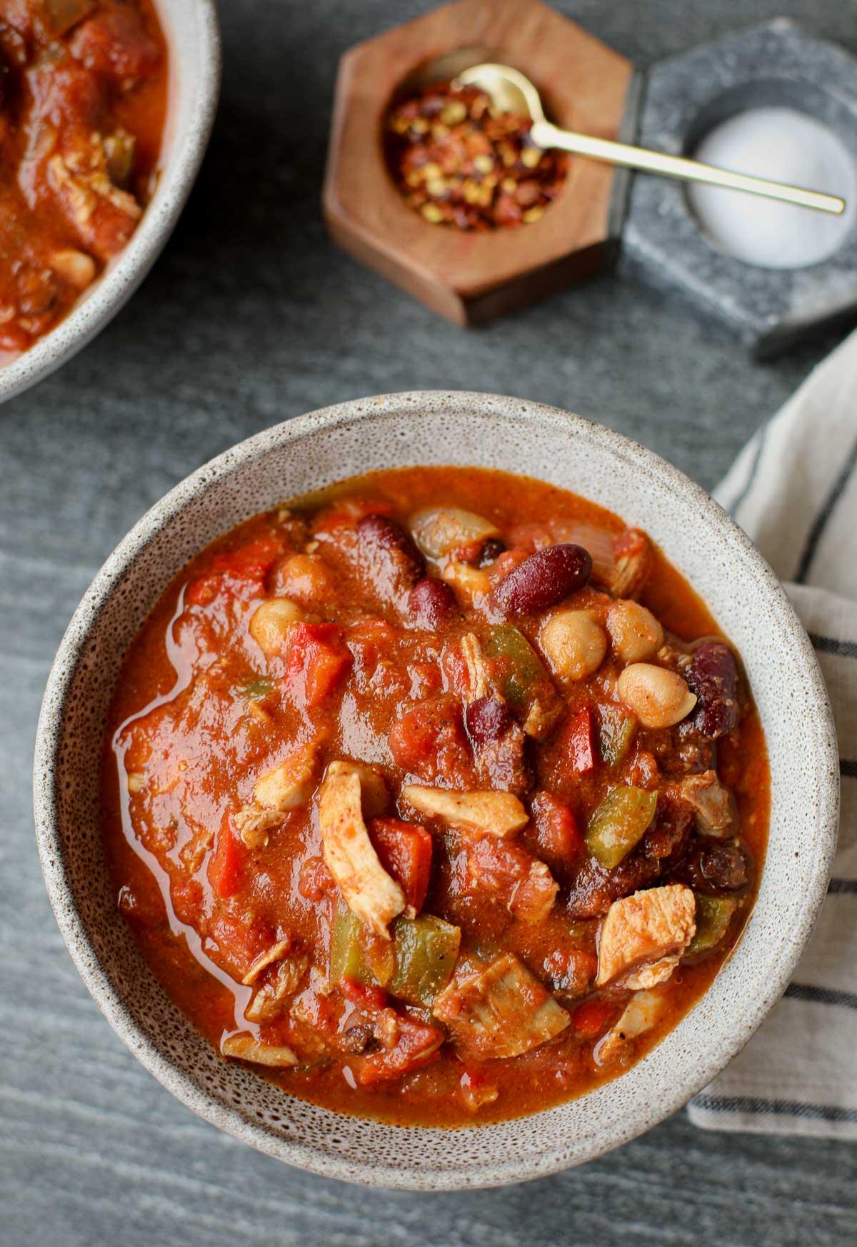 close-up of cooked chicken pieces simmering in a rich, red chili sauce in a Dutch oven